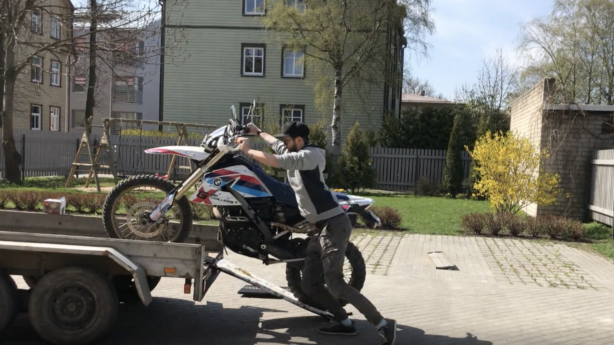 Man loading bike onto trailer using ironing board